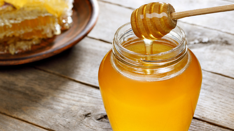 Jar of honey with honeycomb in the background