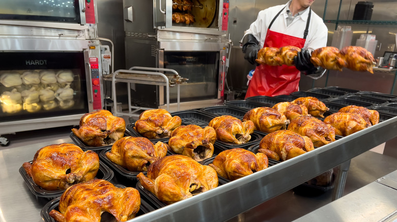 Costco rotisserie chicken being cooked by employee