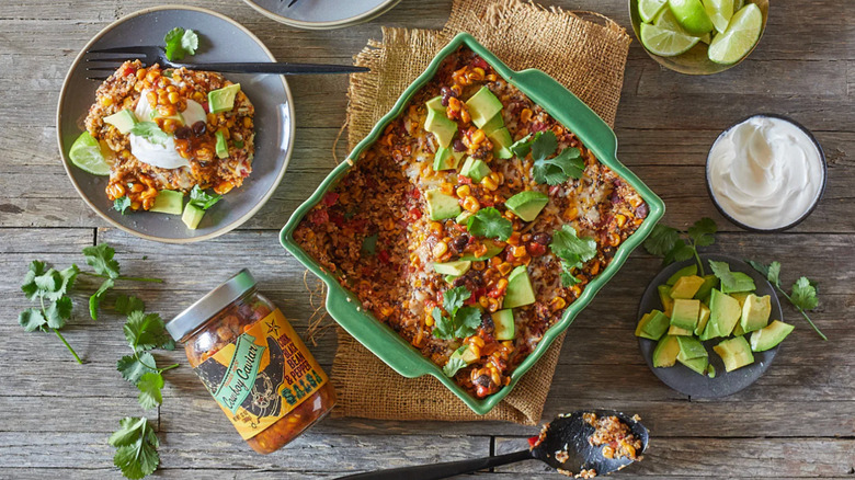 A bean dip next to a jar of cowboy caviar and avocado and cilantro
