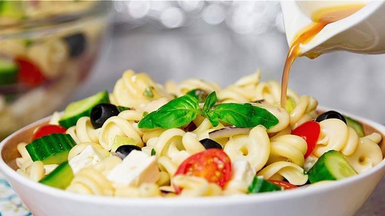 pouring vinaigrette over pasta salad
