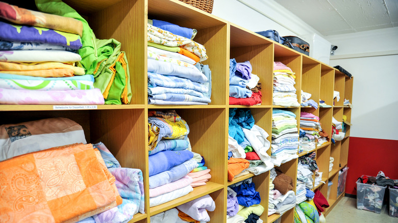 Kitchen linens in a thrift store among other textiles on shelves