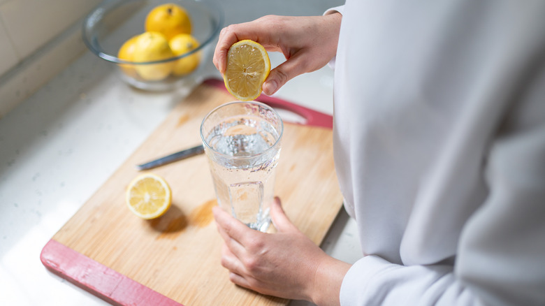 Woman squeezes lemon into water