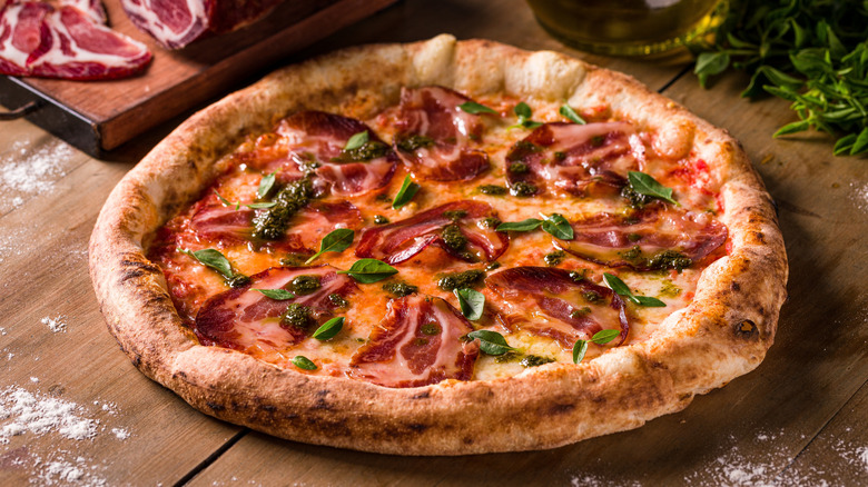 A pizza, covered in slices of coppa ham