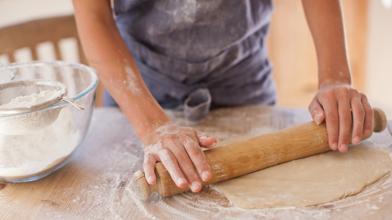 person rolling out dough