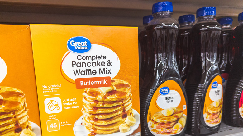 A box of Great Value pancake mix with syrup bottles on shelf