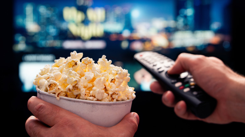 Watching TV with popcorn and a remote.