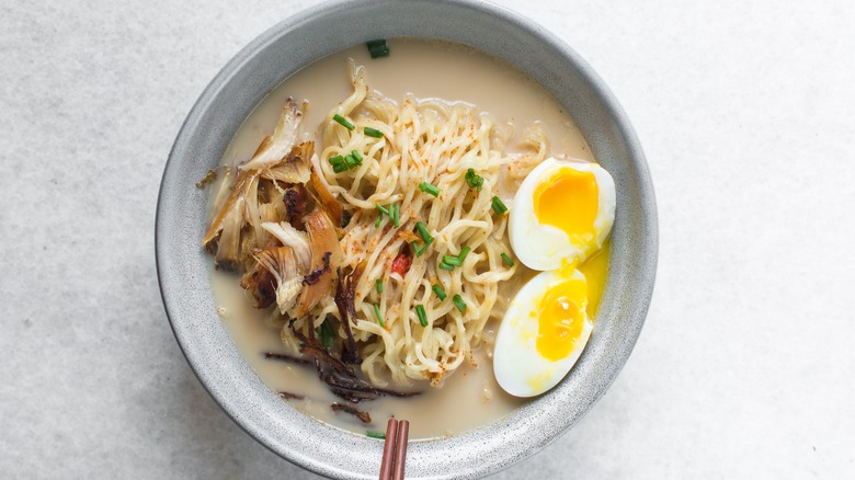 A bowl of creamy ramen noodles with chicken strips and egg