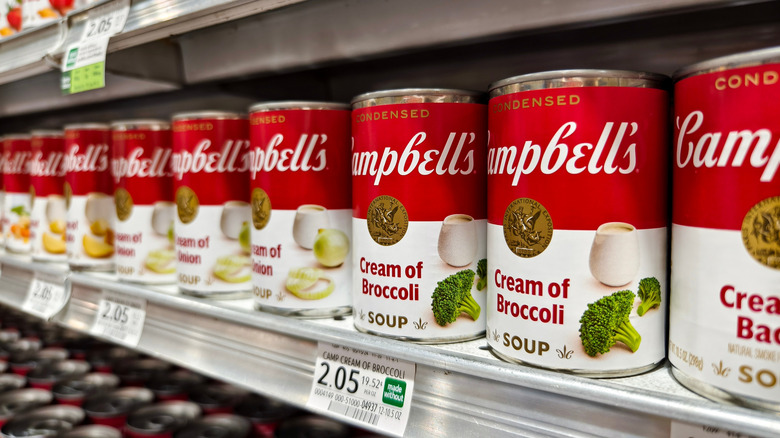 Campbell's soup cans on a supermarket shelf, including cream of broccoli and cream of onion