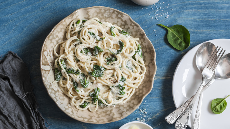 Creamy spinach spaghetti on blue wooden table, top view