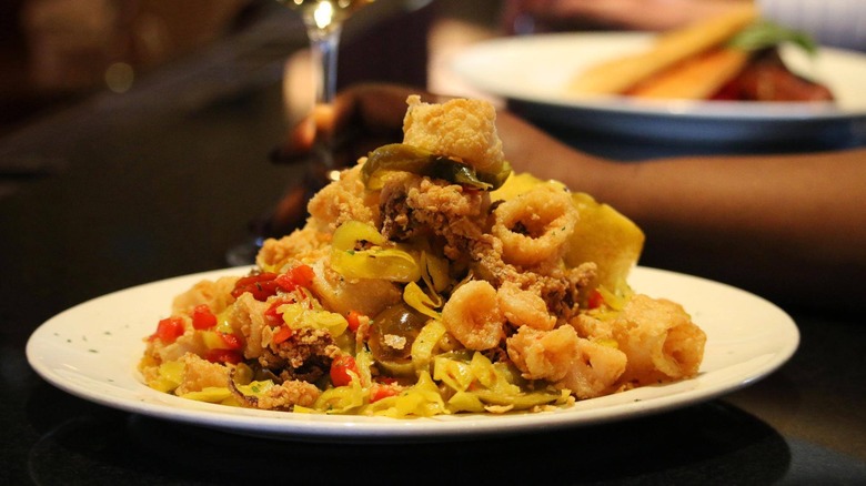 A tall pile of fried calamari with hot cherry peppers on a white dish at The Capital Grille