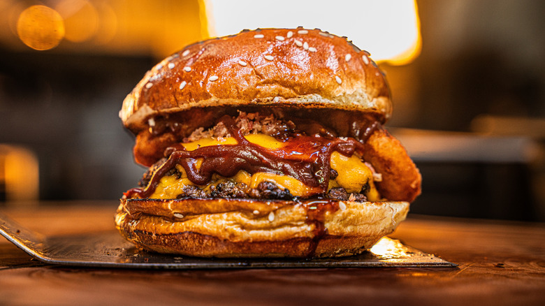 A two-patty smash burger with sauce, cheese, and onion rings