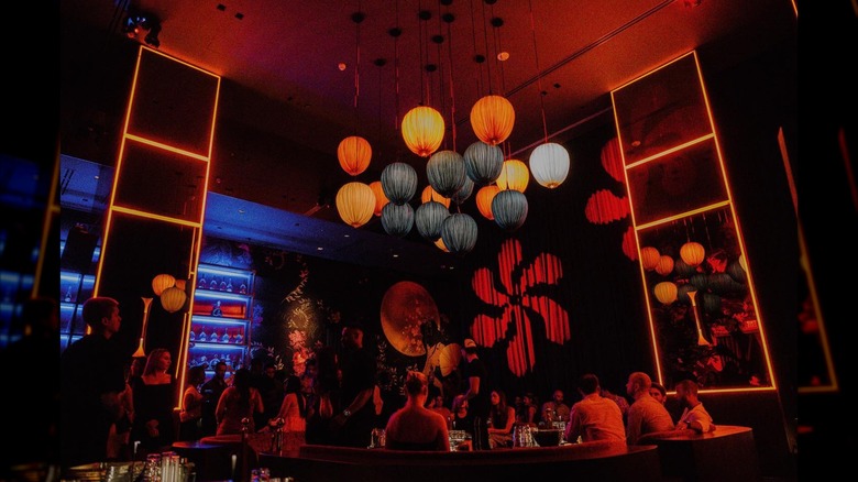 Lounge space at Gekkō, with red lighting, a blue backlit bar, and paper lanterns over center VIP seating