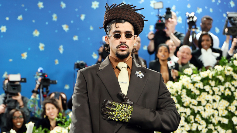 Bad Bunny at the Met Gala wearing hat, suite, sunglasses, and gemstone gloves