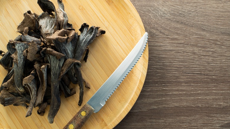 black trumpet mushrooms on board with knife