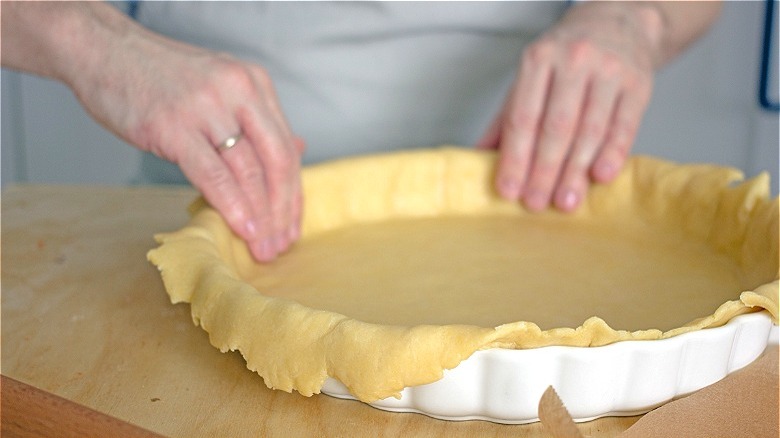 Hands pressing pie dough into pan