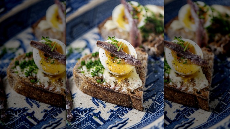 Anchovy atop soft-boiled egg on buttered toast