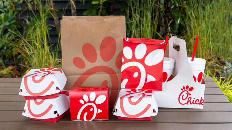 Boxes and bags of Chik-fil-A menu items displayed on a table outdoors