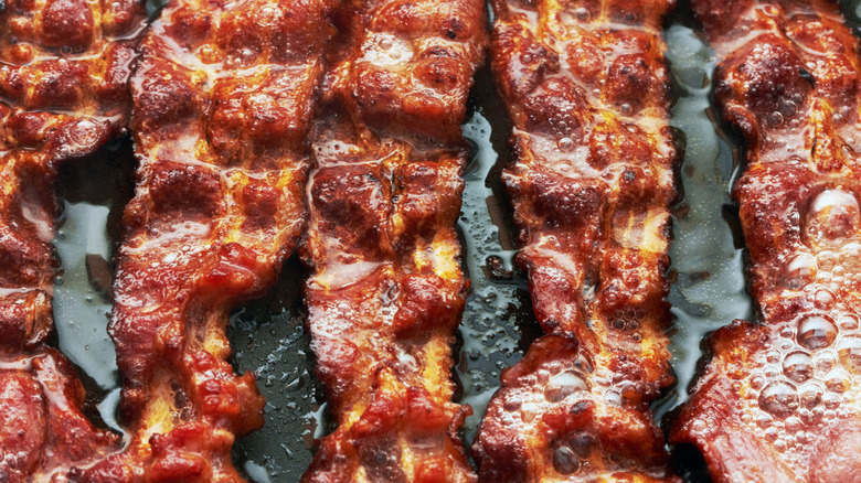 Strips of crispy bacon cooking