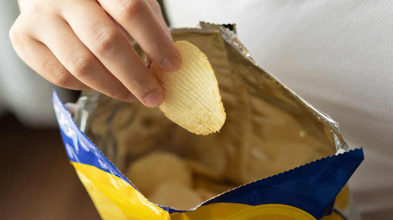 open potato chip bag with hand
