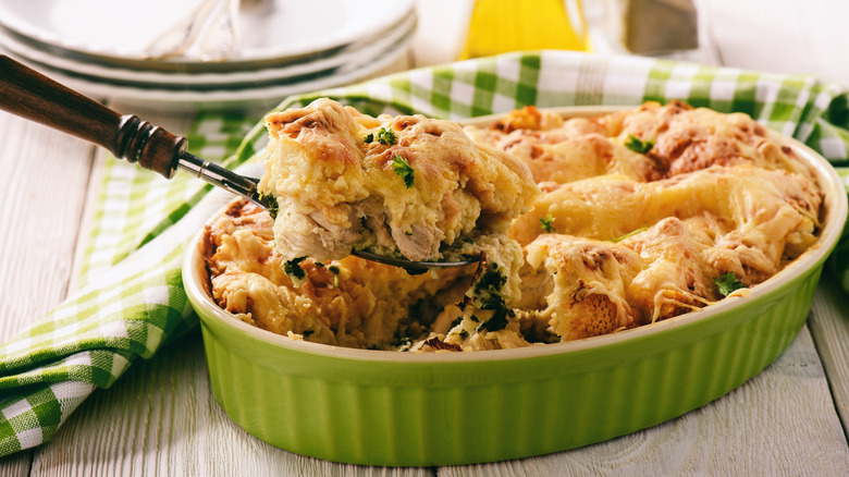 Chicken and cheese strata in a baking dish with serving spoon