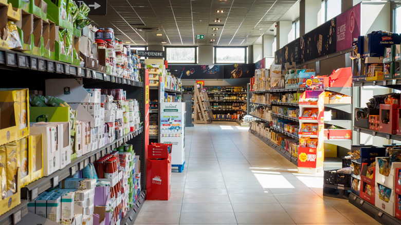 Bright sunlight highlighting product filled shelves inside budget grocery store, showcasing wide selection of affordable ALDI merchandise