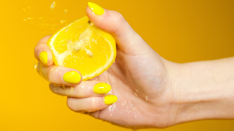 hand squeezing juicy lemon wedge