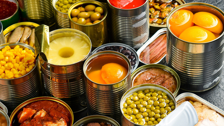 An array of canned foods is placed on a grey table top.