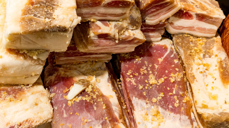 Thick pieces of pork are cured with salt.