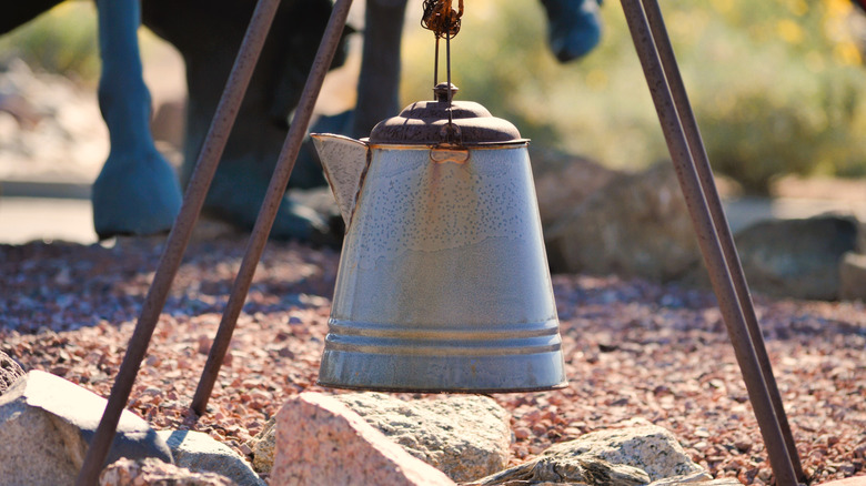 A coffee pot hangs over small fire pit.