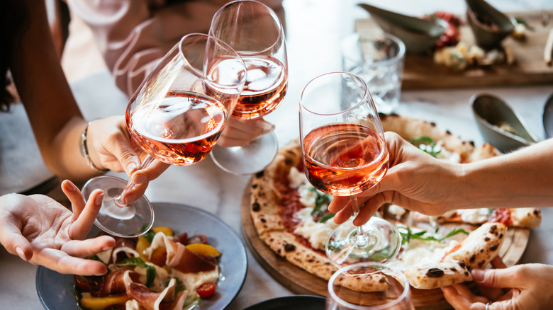 People holding glasses, toasting over food