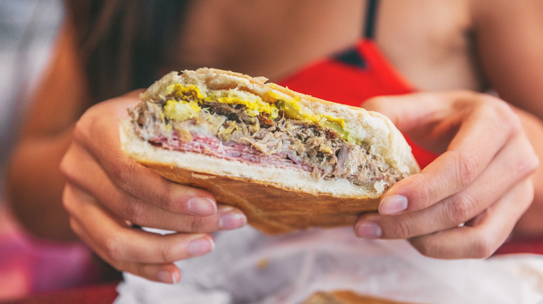 person picking up Cuban sandwich