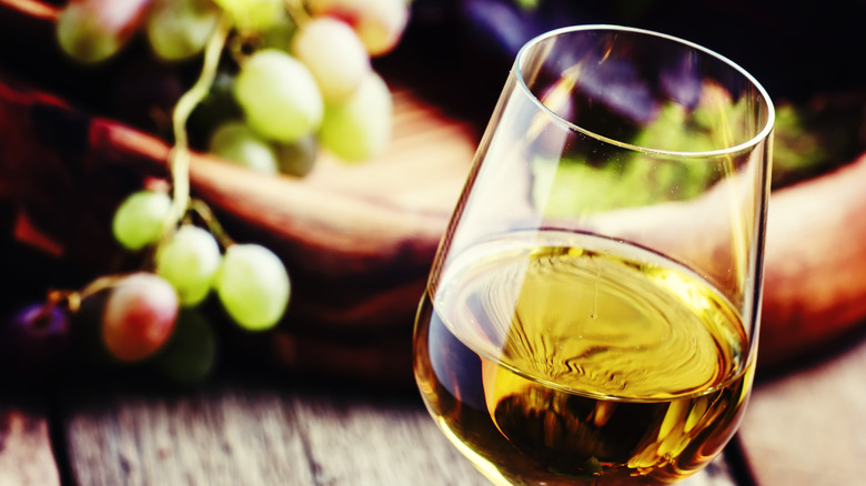 glass of wine with grapes in the background