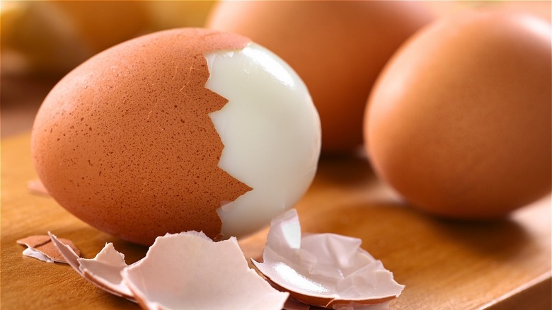 Boiled brown egg with part of shell peeled off