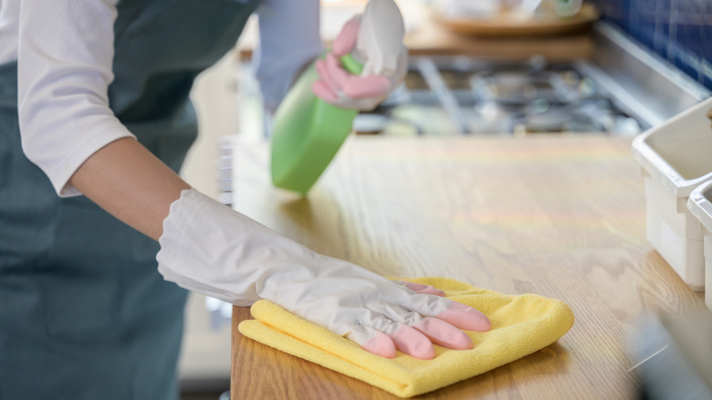 Woman cleaning kitchen with sponge and spray
