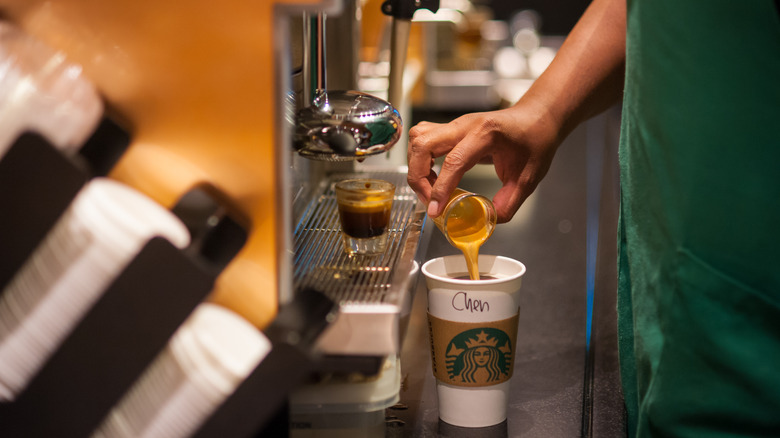 A barista pours espresso into a Starbucks cup