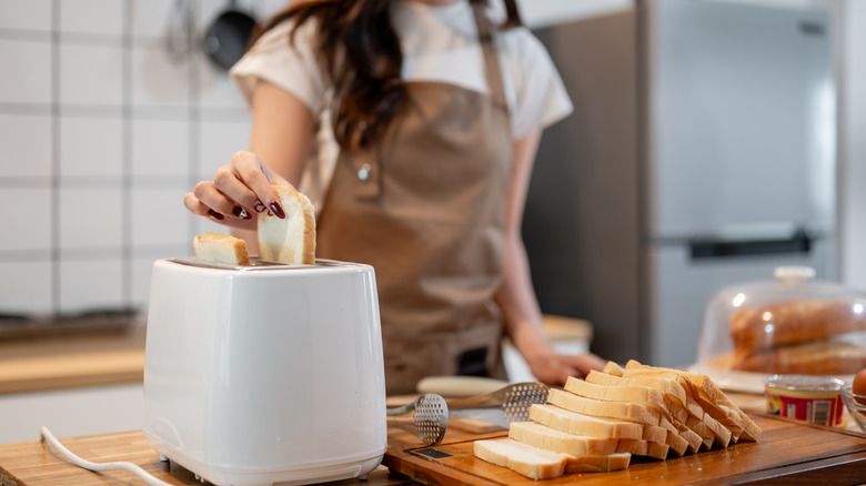 Hand putting bread into toaster