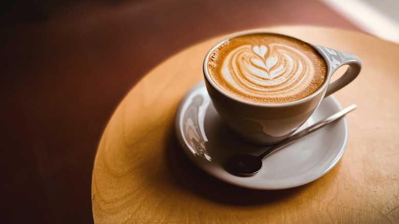 Vanilla latte with design in mug on table
