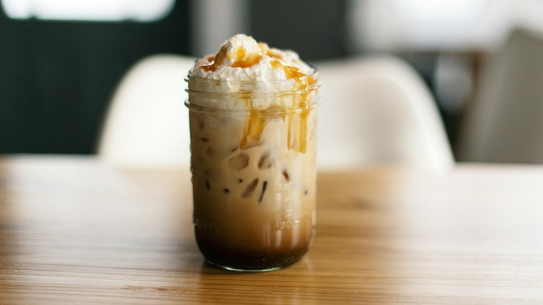 Iced caramel macchiato in Ball jar on wood table