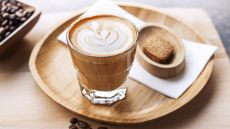 Cortado on wood plate with coffee beans