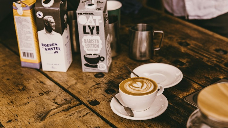 Oat milk cappuccino on wood table with oat milk