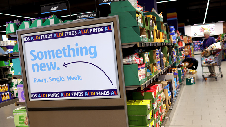 View down an aisle at Aldi, with a sign on the end cap reading "Something new every single week"
