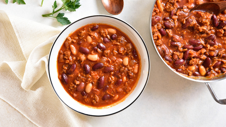 A bowl of chili beside a pot of chili