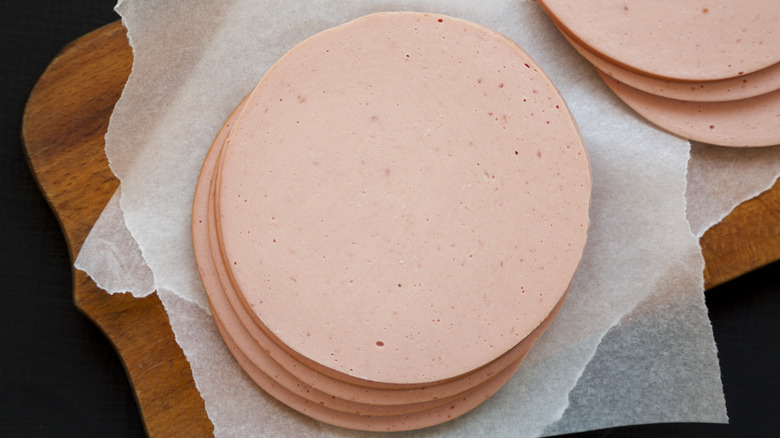 Slices of bologna on parchment paper on wood board