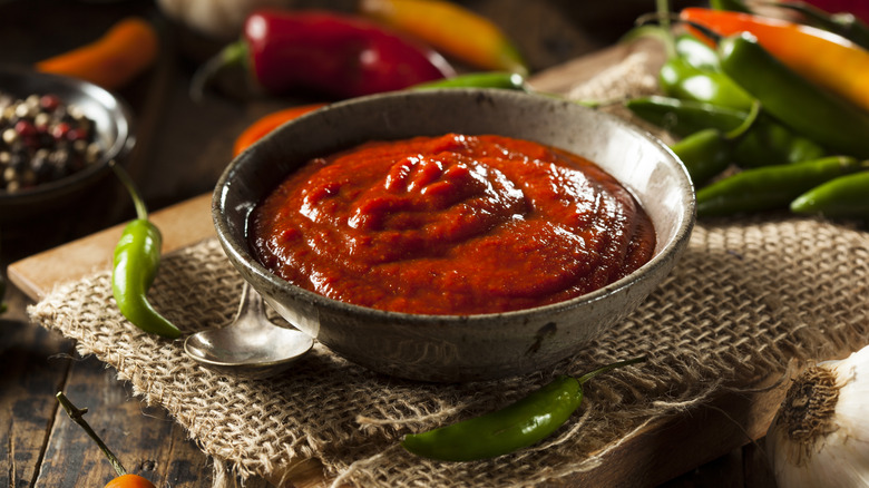 Bowl of Sriracha with peppers in background