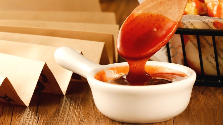 White bowl of sweet-and-sour sauce & wooden spoon