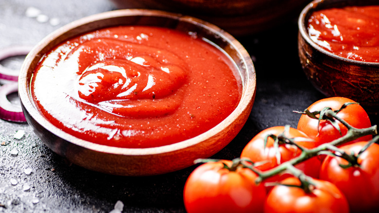 Shallow bowl of ketchup with tomatoes on the side