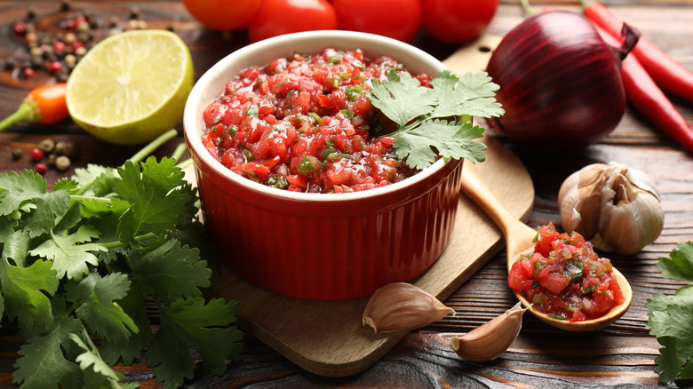 Ramekin with fresh salsa on wooden board