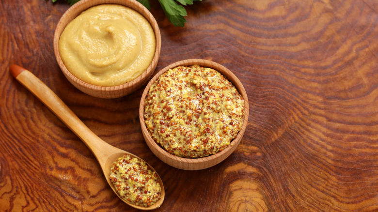 Dijon mustard in wooden cups on wooden table