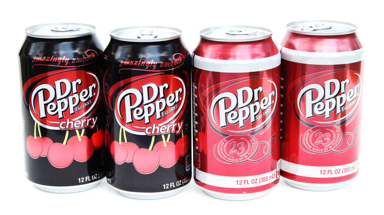 Four cans of Dr Pepper in a line against a white background