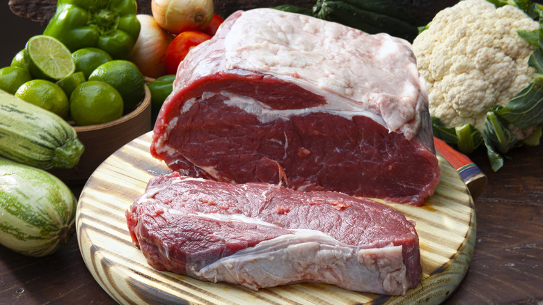 A raw beef strip loin with one thick NY strip steak cut off